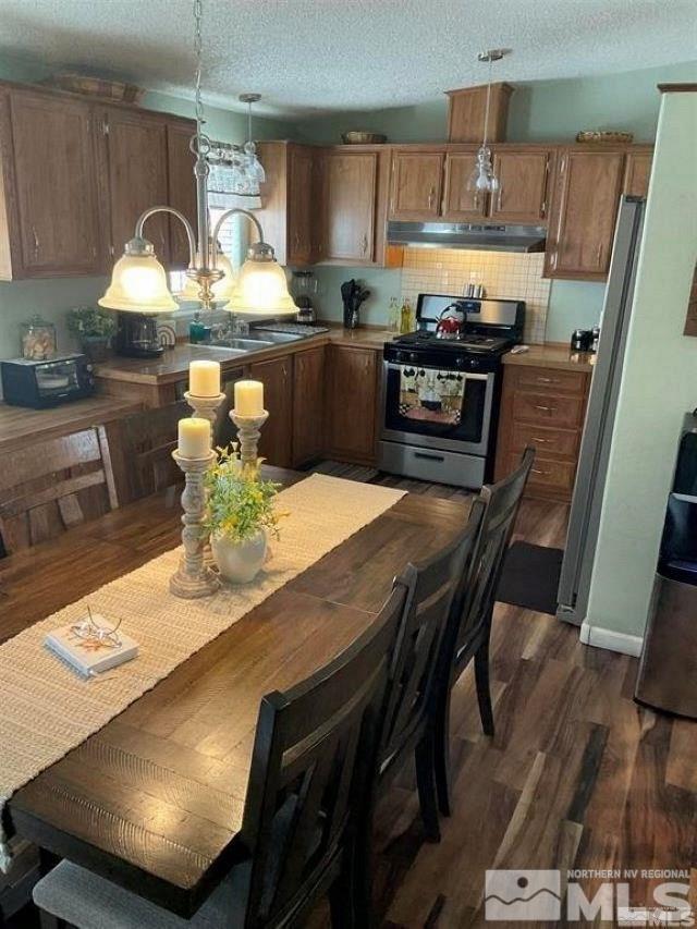 a kitchen with stainless steel appliances granite countertop a sink a stove a kitchen island with chairs and wooden floor