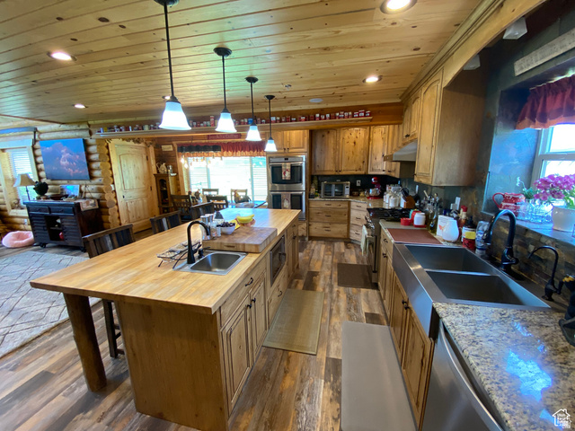 79 Auburn Forest Road Auburn, WY 83111 - Photo 24 of 76 Kitchen featuring an island with sink, rustic walls, a kitchen bar, wooden ceiling, and stainless steel appliances