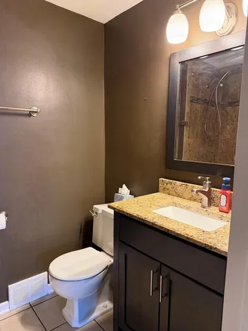 a bathroom with a granite countertop toilet sink and mirror
