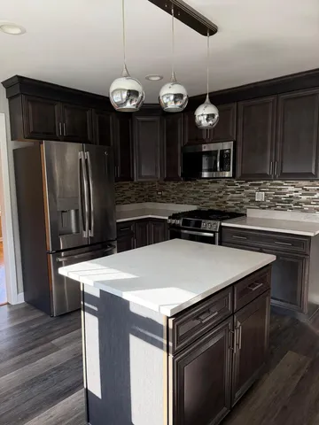 a kitchen with a refrigerator a stove and wooden floor