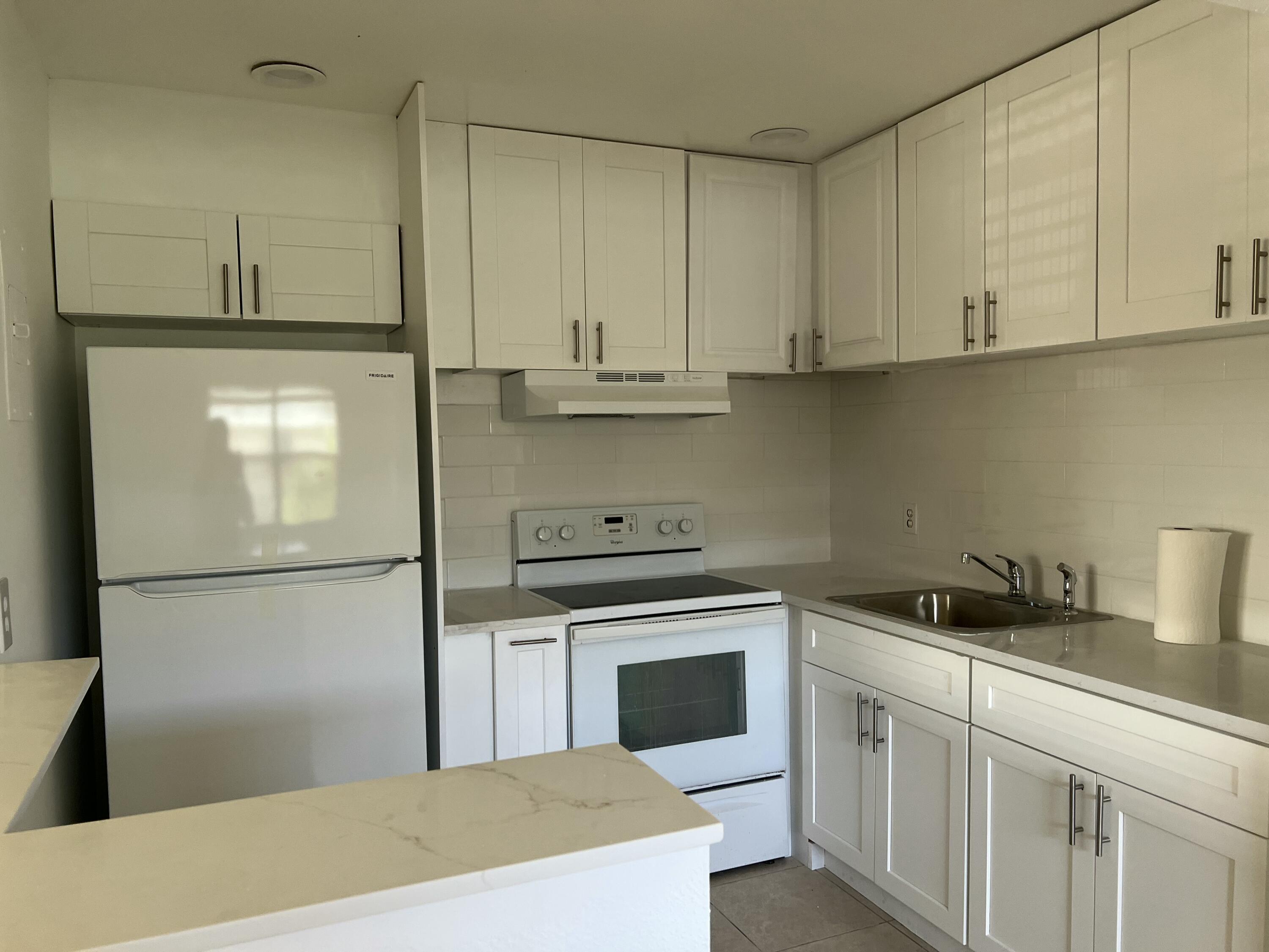 631 Brittany Lane Delray Beach, FL 33446 - Photo 2 of 11 a kitchen with a refrigerator sink and cabinets