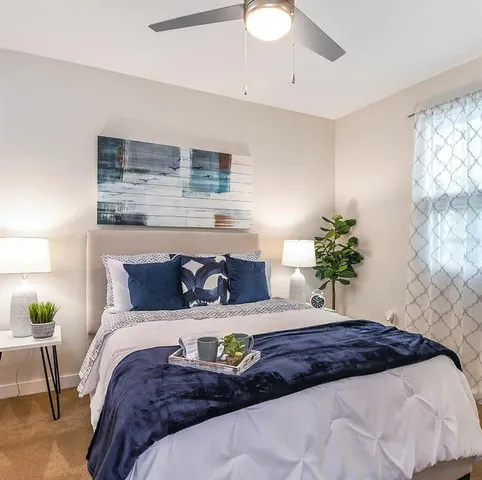 a bedroom with a bed potted plant on dresser and a wooden floor