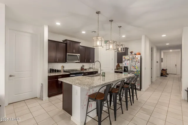 a kitchen with stainless steel appliances a stove a refrigerator a sink a dining table and chairs