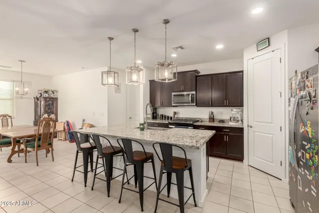 a kitchen with stainless steel appliances a refrigerator a stove a sink a dining table and chairs