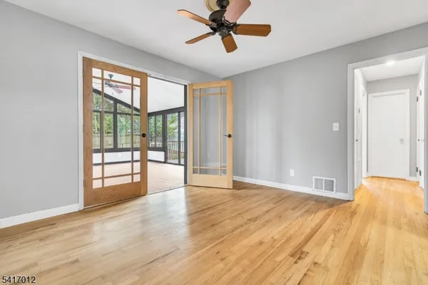 a view of an empty room with wooden floor and a window