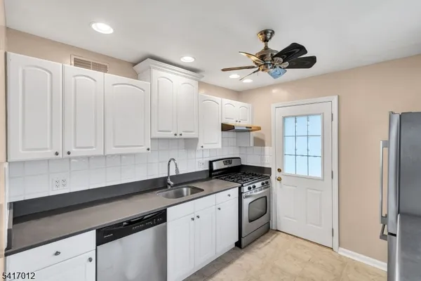 a kitchen with stainless steel appliances granite countertop a sink a stove and cabinets