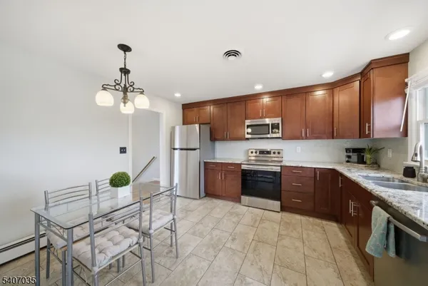 a kitchen with stainless steel appliances granite countertop a refrigerator a sink dishwasher a stove with wooden cabinets and floor