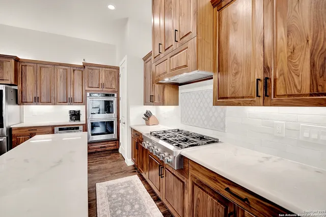a kitchen with stainless steel appliances granite countertop a stove a sink dishwasher and cabinets with wooden floor