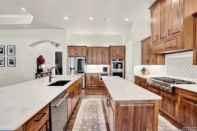 a large kitchen with stainless steel appliances a stove a sink dishwasher and cabinets with wooden floor