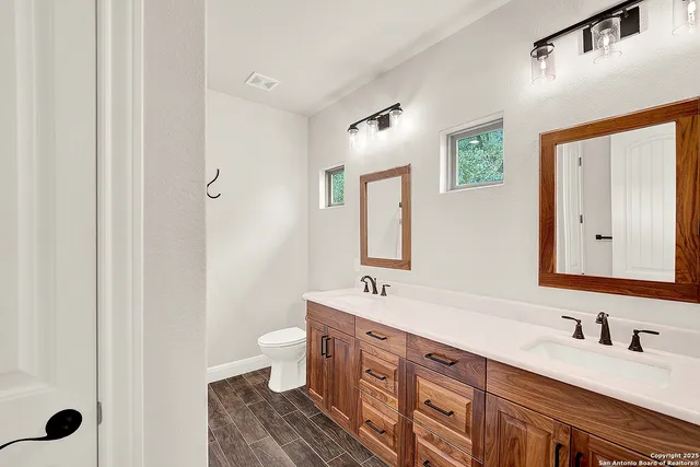 a spacious bathroom with a double vanity sink a mirror and a toilet