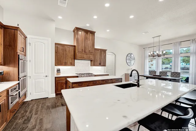 a kitchen with stainless steel appliances a sink a stove a refrigerator cabinets and wooden floor