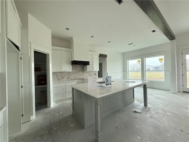 a view of a kitchen with kitchen island a sink stainless steel appliances counter space and living room view