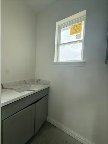 a bathroom with a granite countertop sink vanity and a window