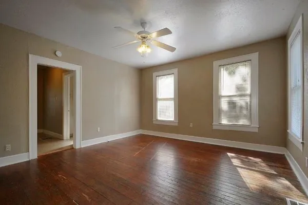 a view of an empty room with wooden floor and a window