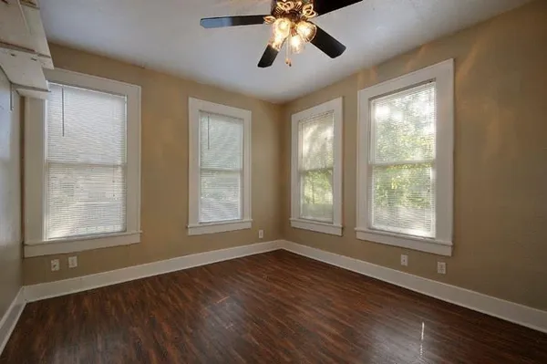 a view of an empty room with wooden floor and a window