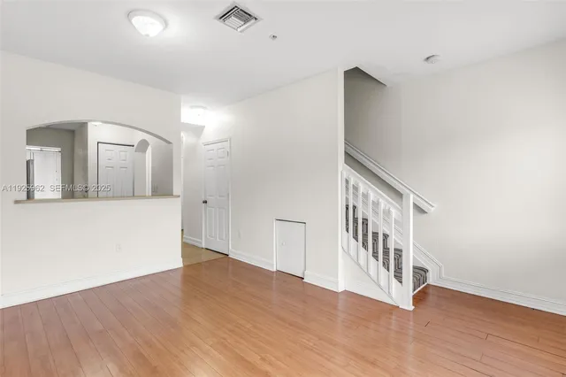 a view of empty room with wooden floor and fan