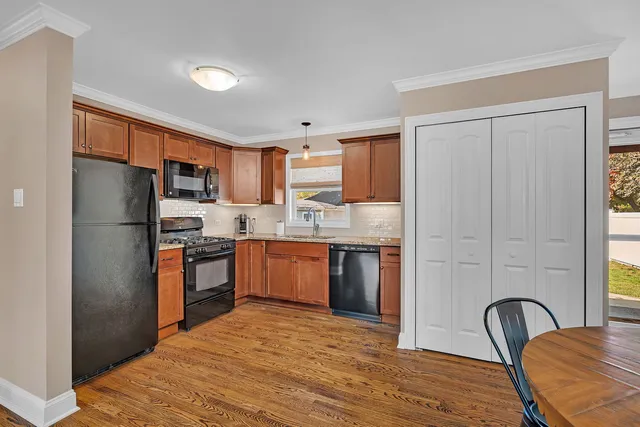 a kitchen with stainless steel appliances granite countertop a refrigerator a stove top oven a sink dishwasher and wooden cabinets with wooden floor