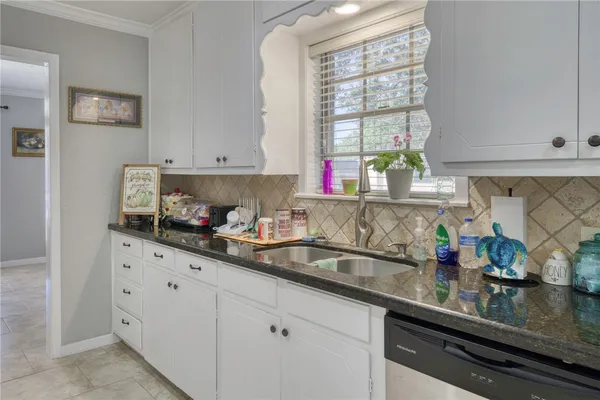 a kitchen with granite countertop white cabinets and window