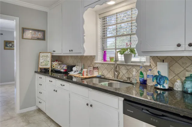 a kitchen with granite countertop white cabinets and window