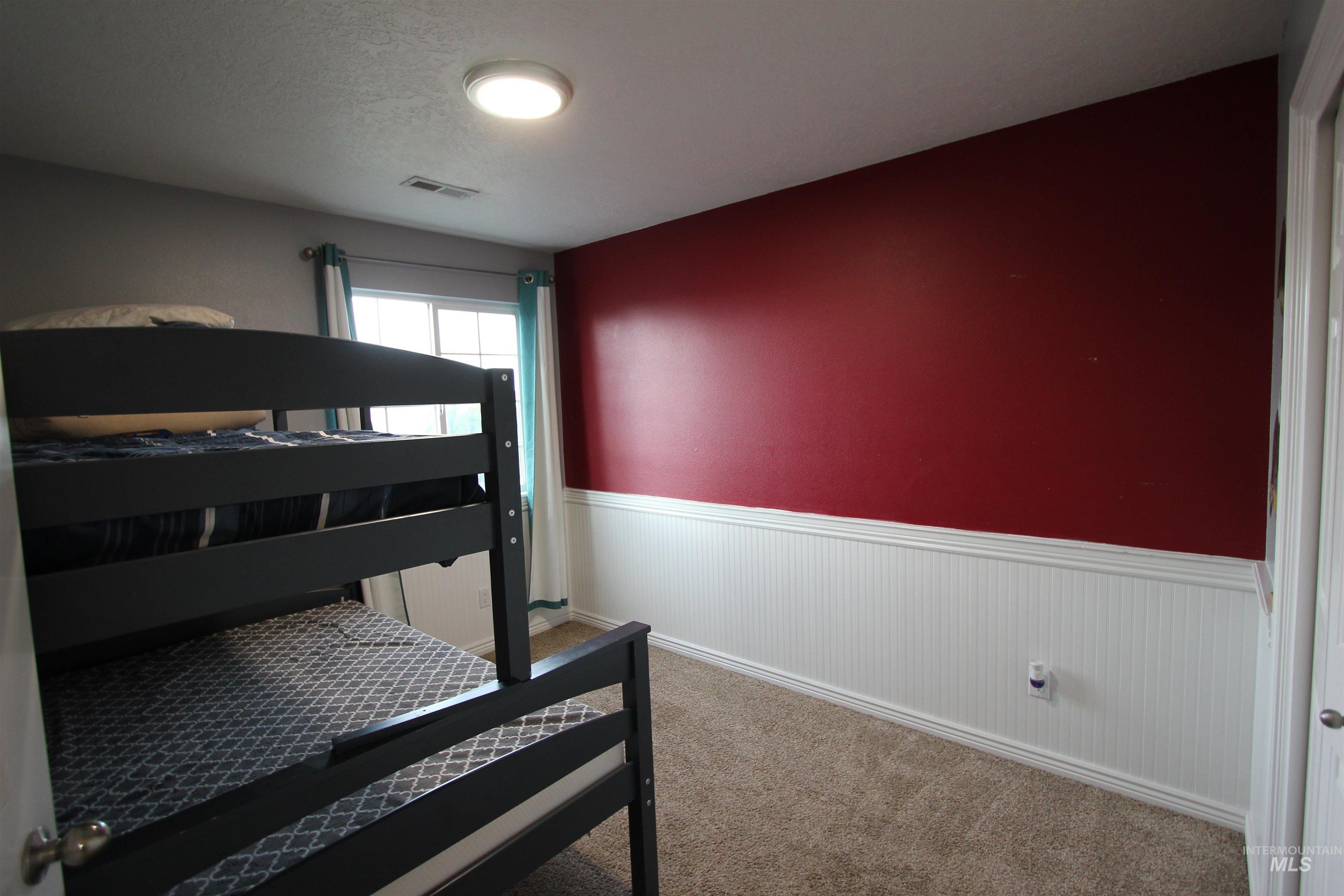 4816 Kadie Street Caldwell, ID 83607 - Photo 19 of 23 Carpeted interior room featuring a window with teal and white curtains, a white ceiling, and a wall with red paint above white beadboard paneling