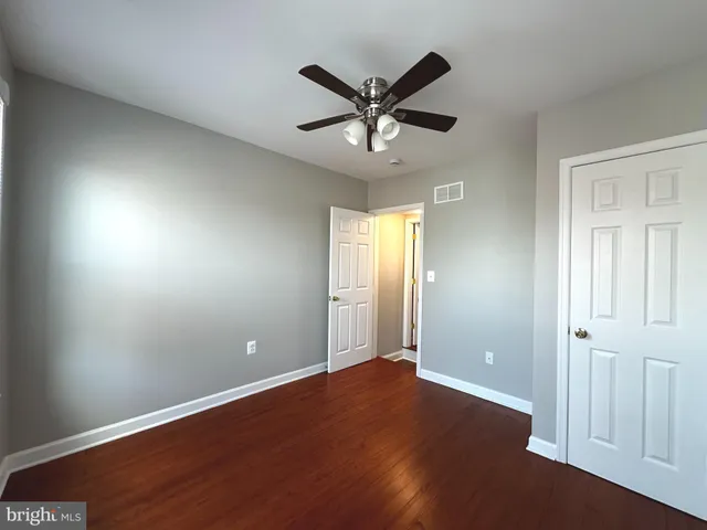 an empty room with wooden floor fan and windows