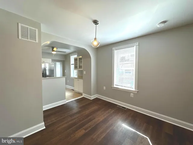 an empty room with wooden floor chandelier fan and windows