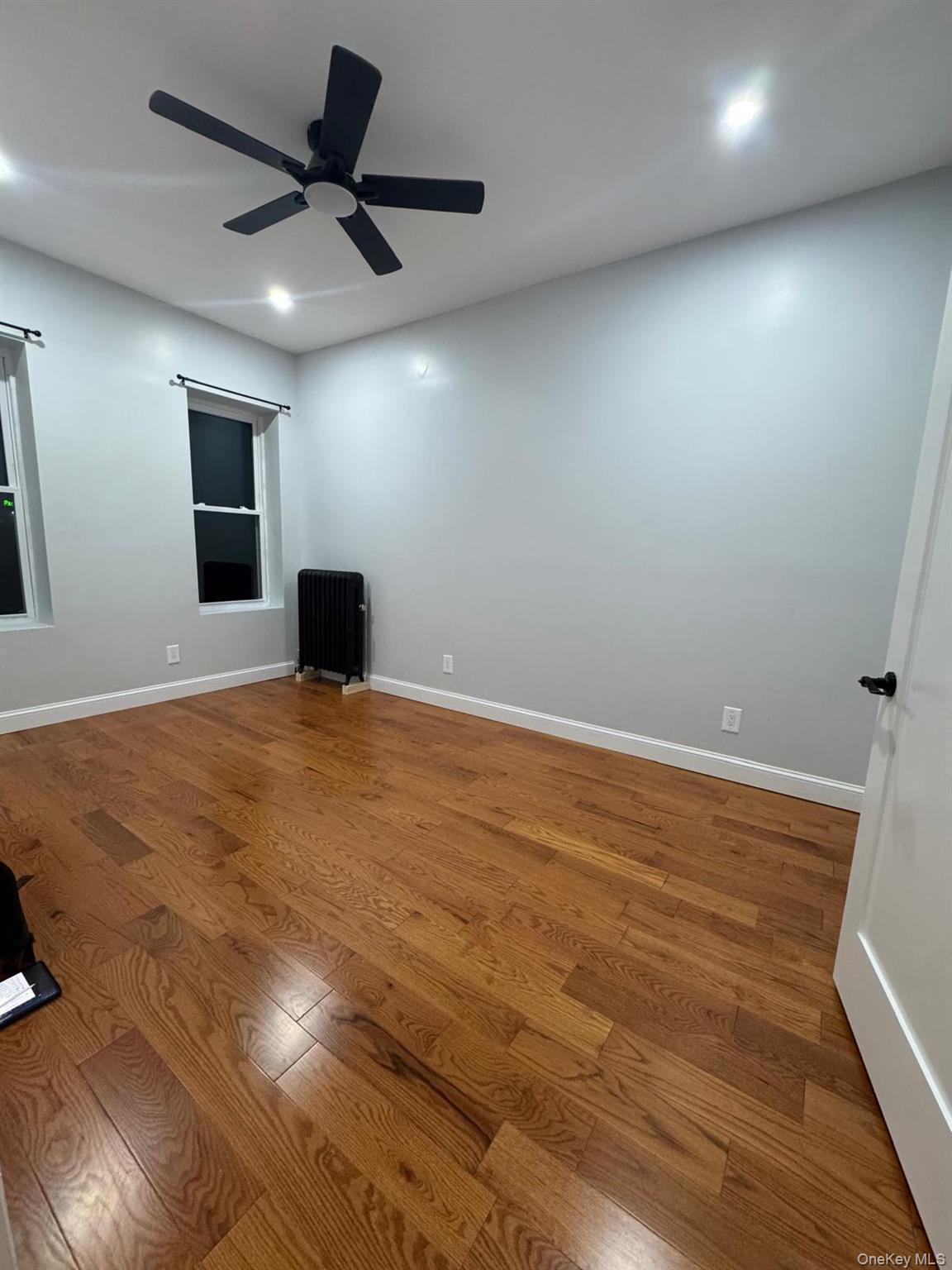 168-11 88th Avenue Queens, NY 11432 - Photo 1 of 5 an empty room with a ceiling fan and window
