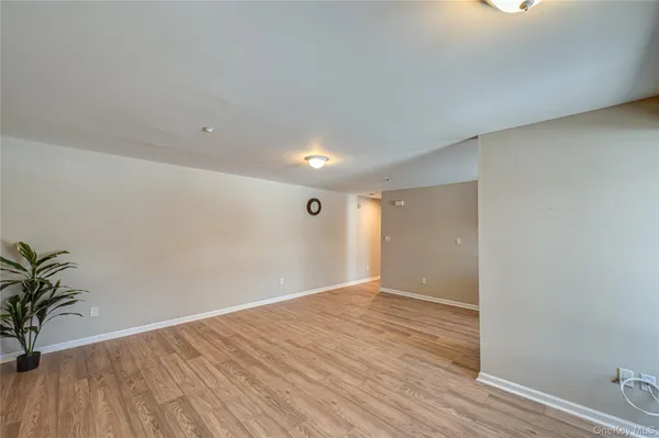 a view of an empty room with wooden floor and glass door