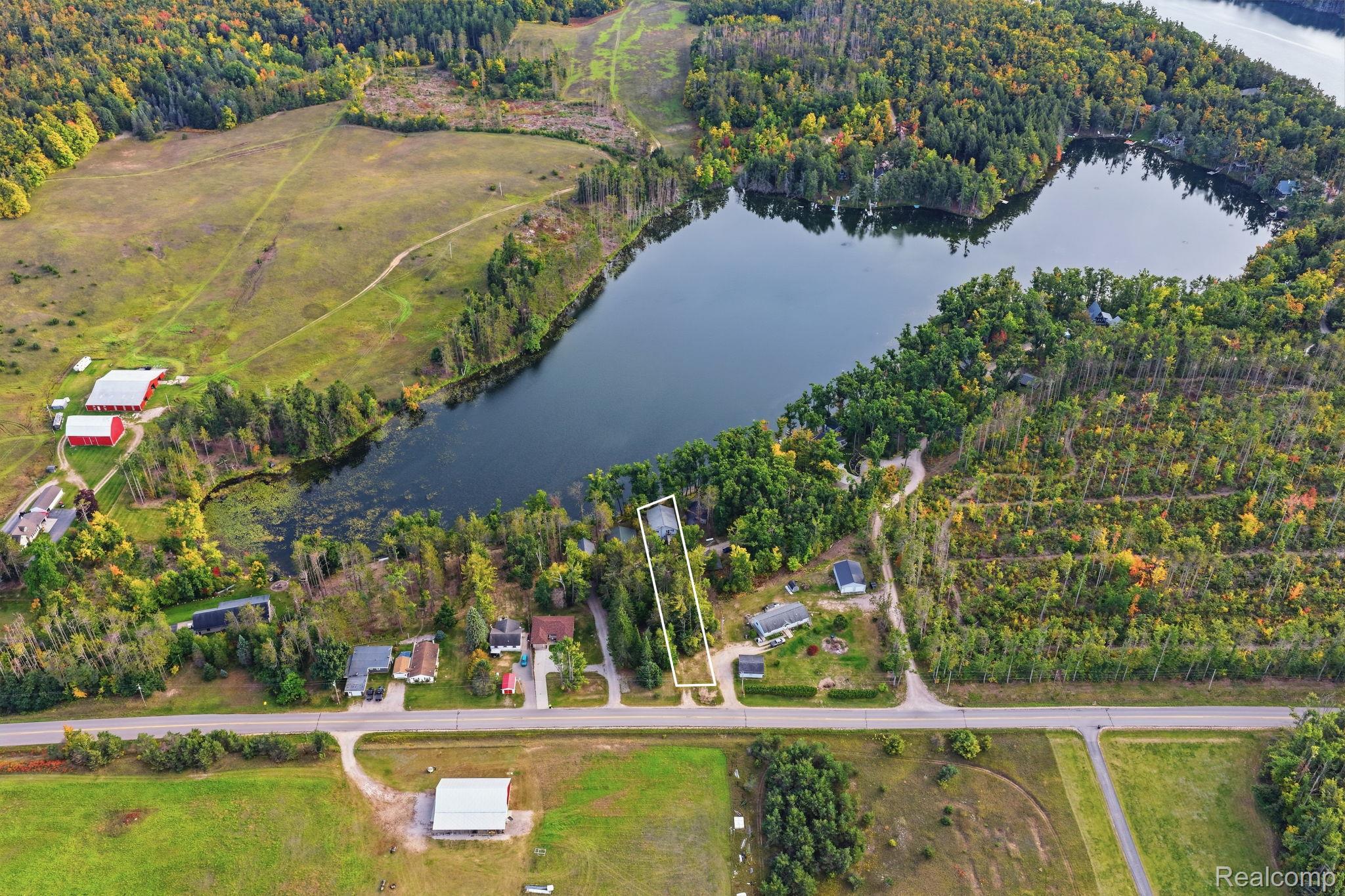 2259 Kassuba Road Gaylord, MI 49735 - Photo 43 of 46 Aerial perspective showcasing a parcel with direct water access, surrounded by mature trees, and bordered by a paved road