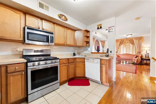 a kitchen with stainless steel appliances granite countertop a stove top oven a sink dishwasher and cabinets with wooden floor