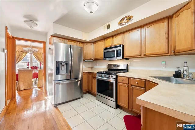 a kitchen with stainless steel appliances granite countertop a refrigerator oven a sink dishwasher and white cabinets with wooden floor