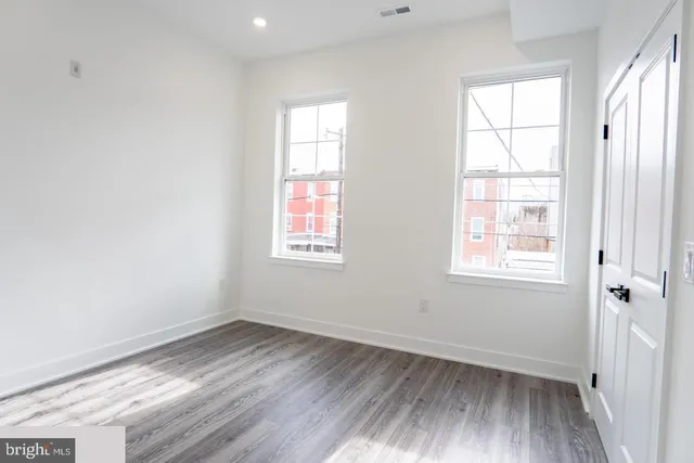 an empty room with wooden floor and windows