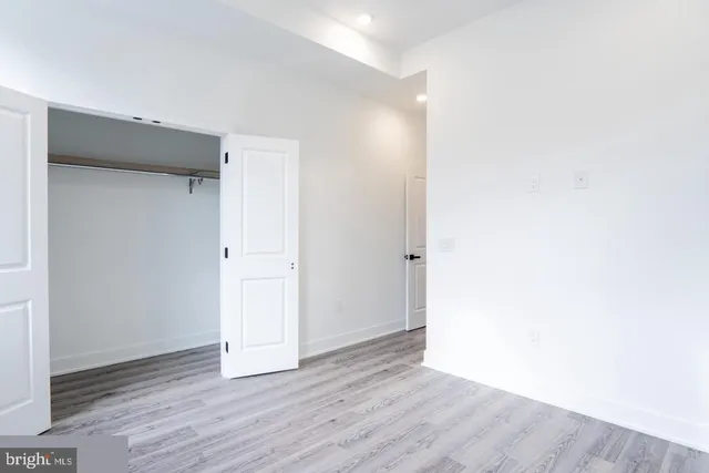 a view of an empty room with wooden floor and closet