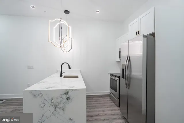 a kitchen with stainless steel appliances granite countertop a sink a stove and refrigerator