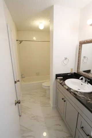 a bathroom with a granite countertop sink toilet and shower