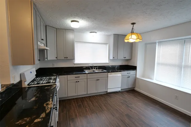 a kitchen with granite countertop a stove a sink and a window