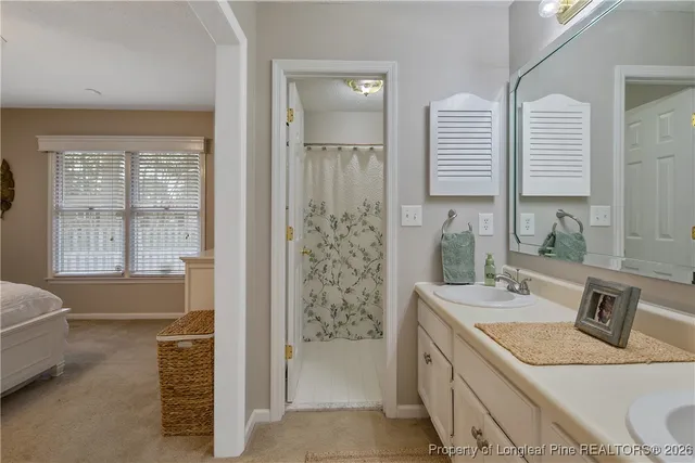 a bathroom with a granite countertop sink a mirror a bathtub and next to a window