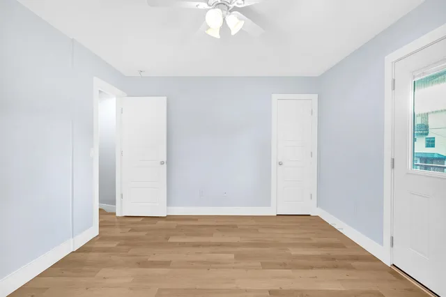 a view of an empty room with wooden floor and a window