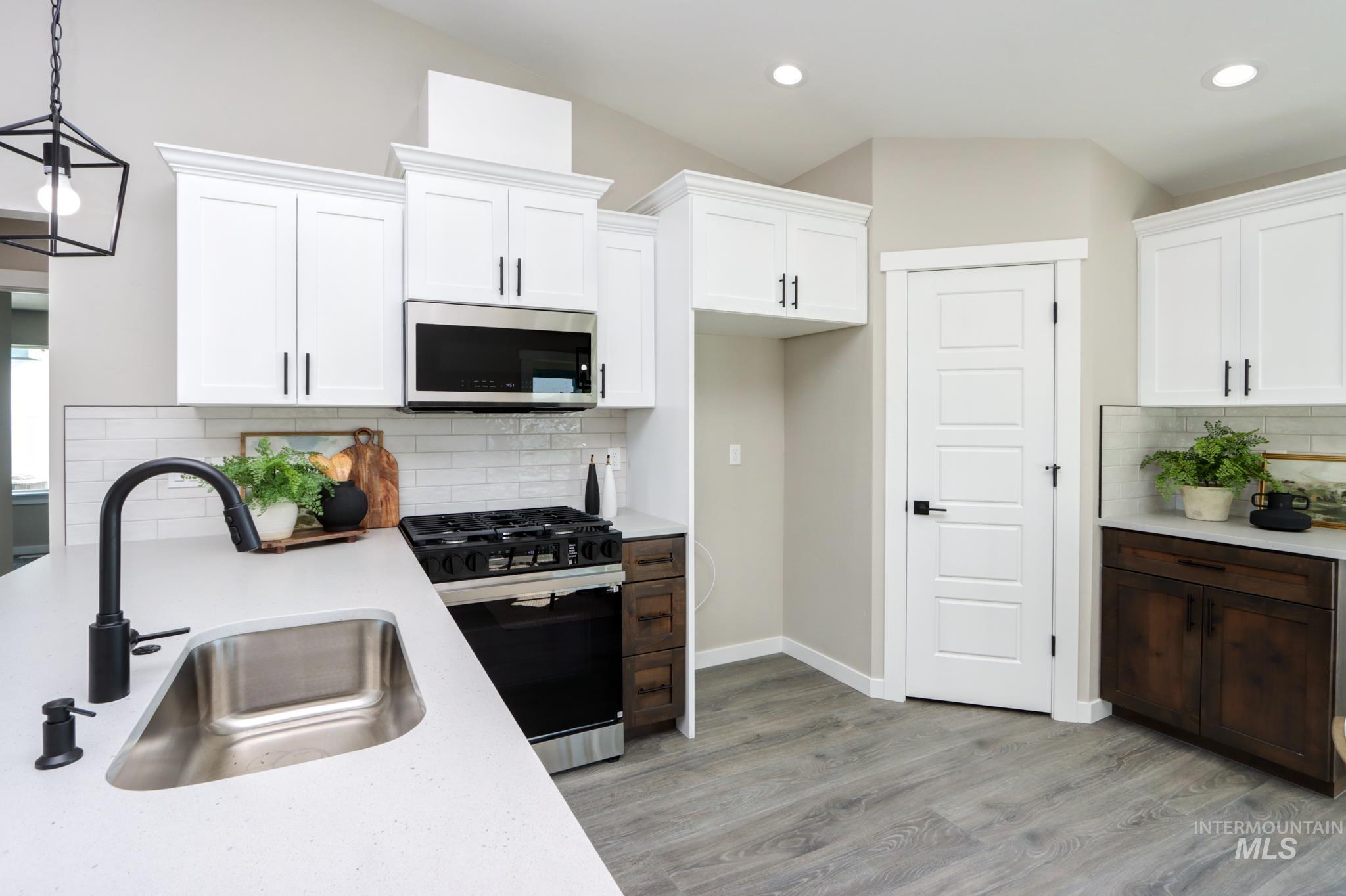 848 North 5th Street Nyssa, OR 97913 - Photo 2 of 49 Kitchen featuring white shaker cabinetry, stainless steel appliances, a white subway tile backsplash, light wood-finish flooring, and a stone countertop with an integrated sink