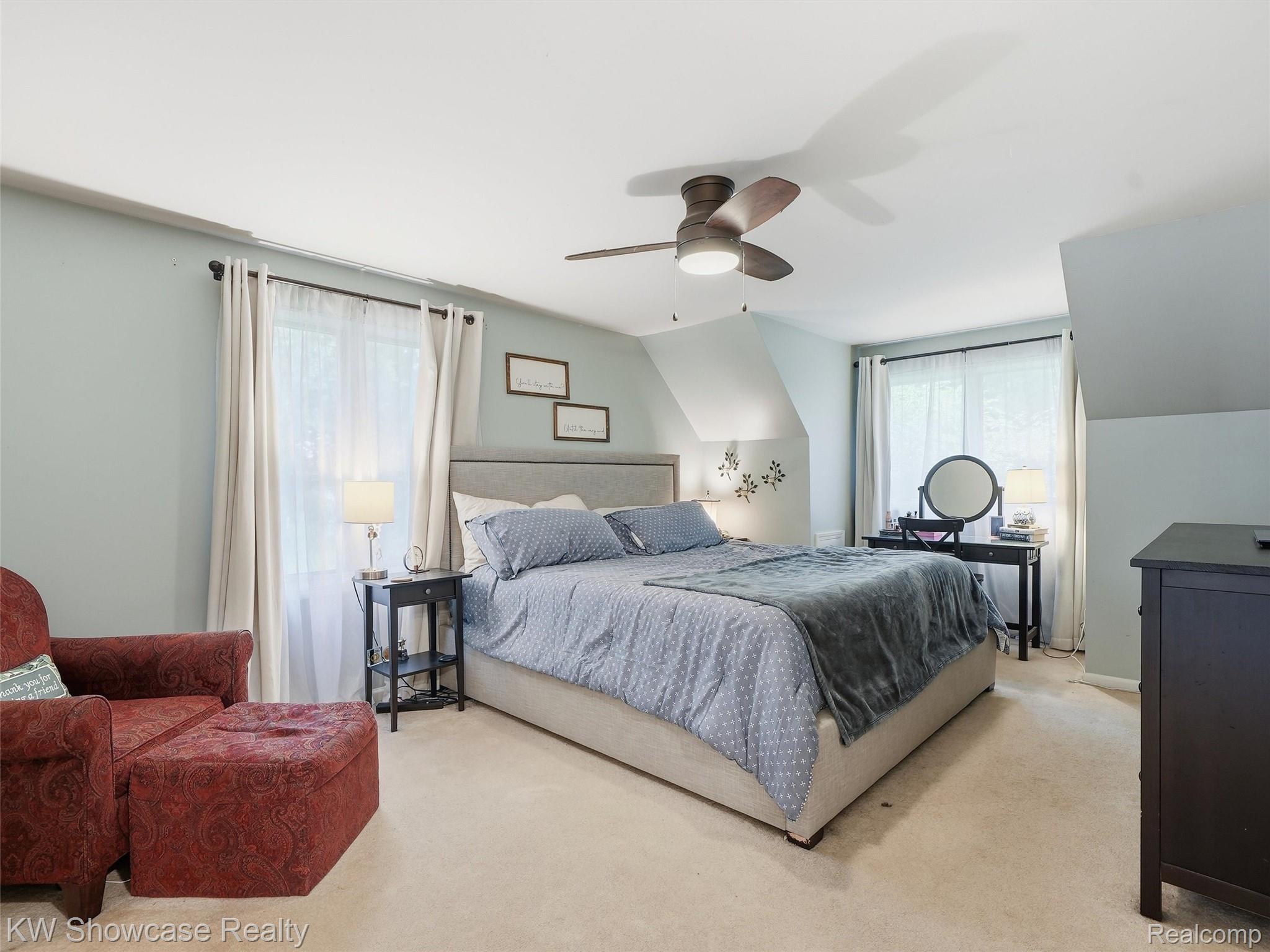 3360 Pleasant Valley Road Brighton, MI 48114 - Photo 29 of 60 Spacious room featuring a centered bed with an upholstered headboard, light blue wall paint, and a ceiling fan with integrated lighting