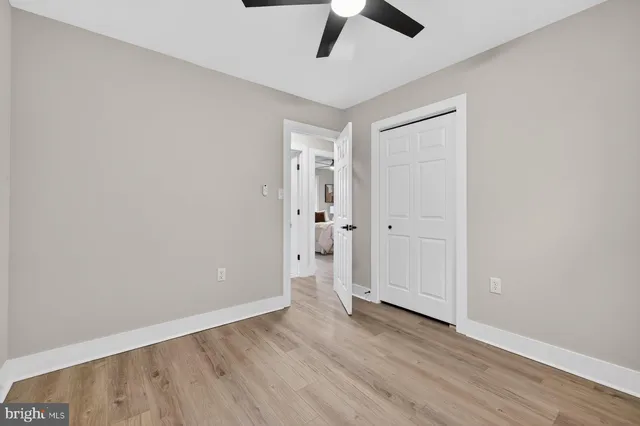 an empty room with wooden floor and ceiling fan