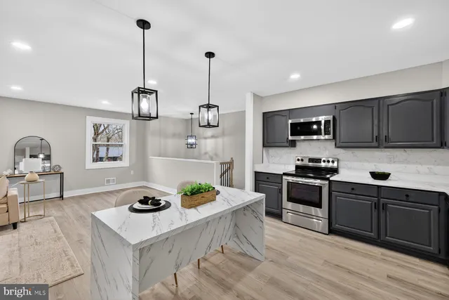 a kitchen with stainless steel appliances a stove a sink a stove a refrigerator white cabinets and wooden floor