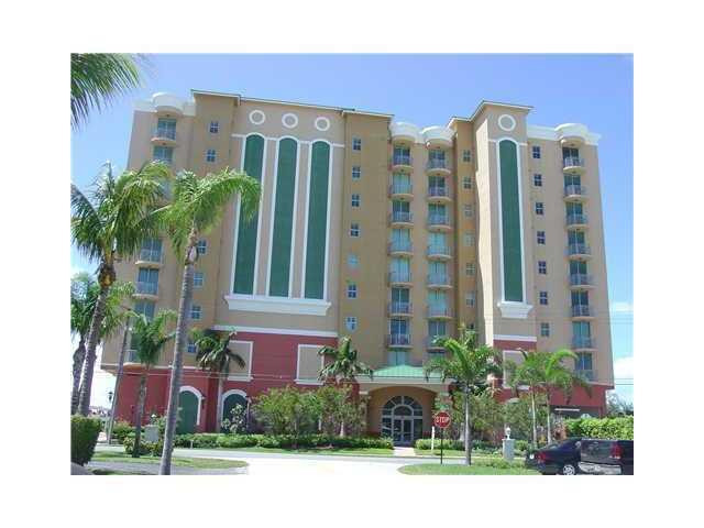 a front view of multi story residential apartment building with yard and parking