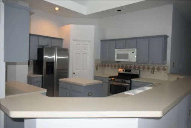 a kitchen with kitchen island a refrigerator a stove and a sink