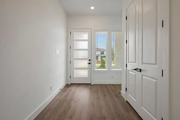 a view of kitchen with stainless steel appliances granite countertop a stove a refrigerator a oven and white cabinets with wooden floor