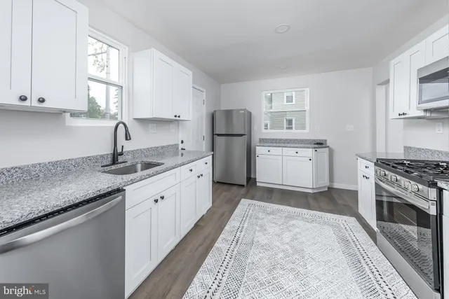 a kitchen with granite countertop a sink stove and cabinets