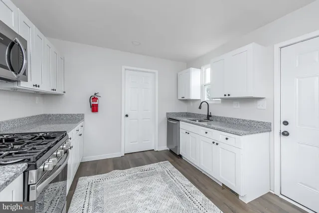 a kitchen with granite countertop a sink stove top oven and cabinets
