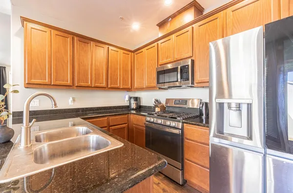 a kitchen with stainless steel appliances granite countertop a sink stove and refrigerator