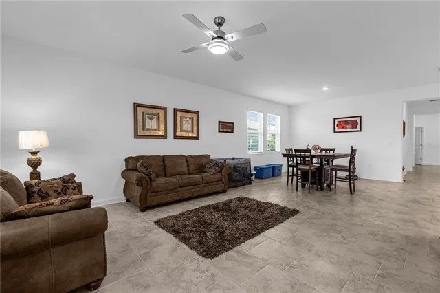 a living room with furniture and a dining table with bookshelf