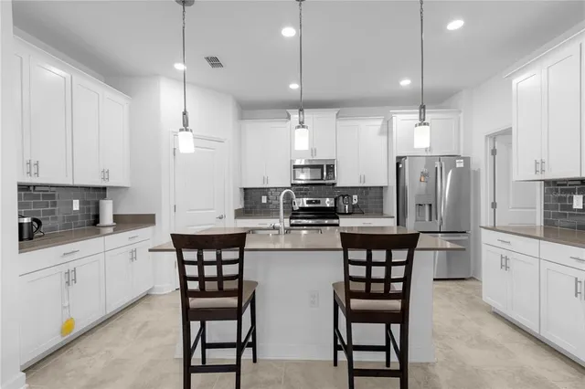 a kitchen with stainless steel appliances a table chairs sink refrigerator and microwave